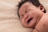 Crying baby with lots of hair and eyes closed