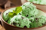 Brown bowl with scoops of  green mint chocolate chip ice cream and a fresh sprig of mint